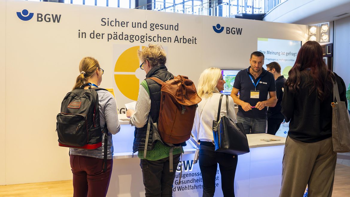 Mehrere Personen an der Infotheke BGW forum 2026 "Sicher und gesund in der pädagogischen Arbeit" in Köln.