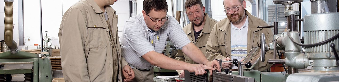Beschäftigte lernen in einer Werkstatt das Arbeiten an einer Maschine