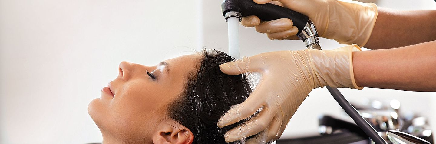 Friseurin wäscht Haare einer Kundin Einer Friseurkundin werden die Haare gewaschen
