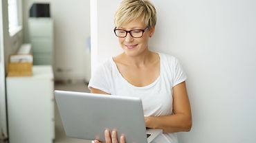 Frau am Laptop Frau hält ein aufgeklapptes Notebook und schaut auf den Bildschirm.