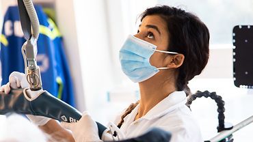 Schülerstation im BG Klinikum Hamburg Eine Pflegeschülerin bedient den Patientenlifter. Sie trägt eine medizinische Maske.
