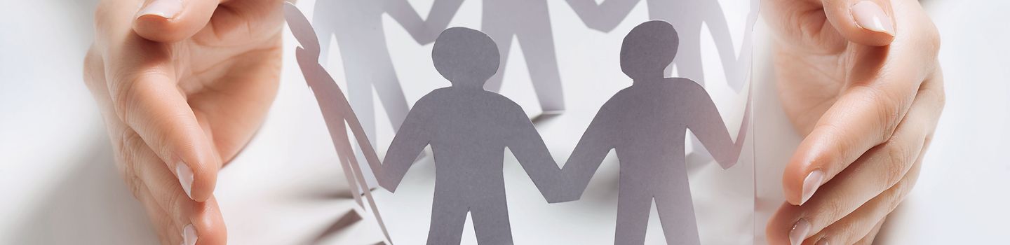 Führung und Gesundheit Zwei Hände halten schützend einen Kreis von Papierfiguren