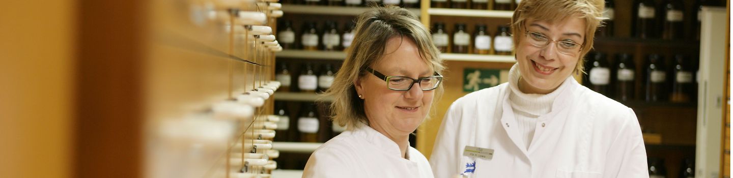 Service für Apotheken Zwei Apothekenmitarbeiterinnen suchen Medikamente aus dem Sortiment.