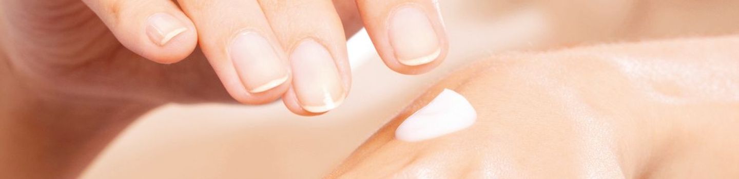 Ein Klecks Hautcreme auf dem Handrücken einer Frau - ihre andere Hand schwebt darüber.