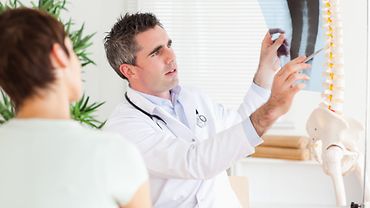 Orthopäde erklärt Patientin Röntgenbild mit Wirbelsäule Orthopäde erklärt Patientin Röntgenbild mit Wirbelsäule