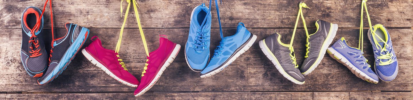 Auswahl an Sportschuhen aufgehängt an Holzwand Auswahl an Sportschuhen aufgehängt an Holzwand