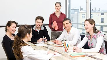 Arbeitssituationsanalyse Team am Tisch diskutiert miteinander.