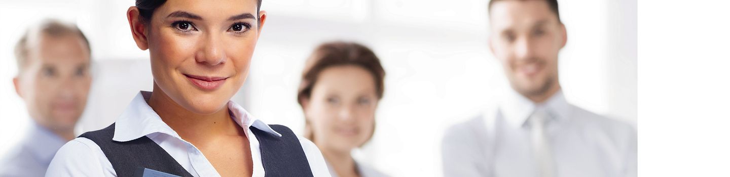 BGW Personalentwicklung "Gesundheitsförderung durch Personalentwicklung" Junge Frau mit Mappe im Arm - im Hintergrund drei weitere Personen