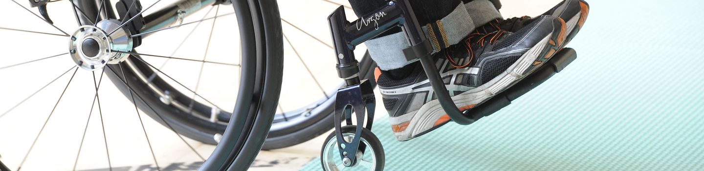 Mobilität Gekippter Rollstuhl Bildausschnitt: Auf die Hinterräder gekippter Rollstuhl mit Person