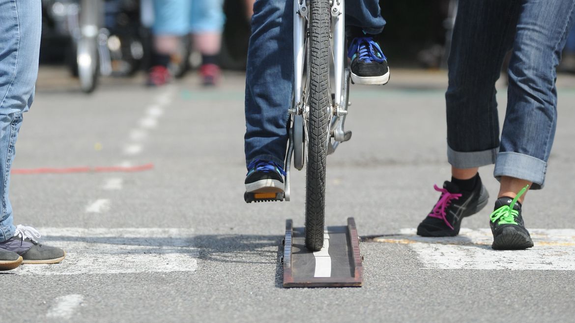 Trainerinnen führen Teilnehmerin des Fahrradtrainings über ein schmales Hindernis.