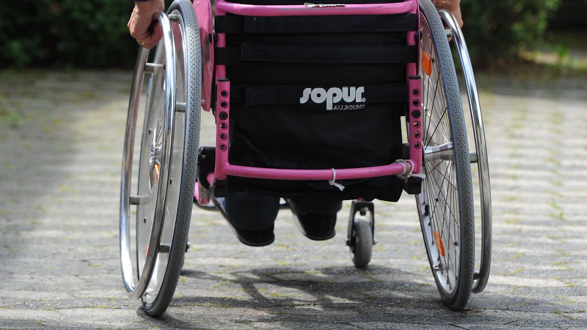 Rollstuhl wird rückwärts über den Bordstein bewegt.