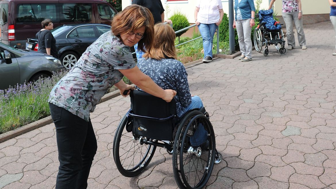 Teilnehmende üben das richtige Schieben eines Rollstuhls.