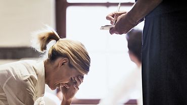 Frau sitzt verzweifelt vor einer anderen Person, die etwas aufschreibt.