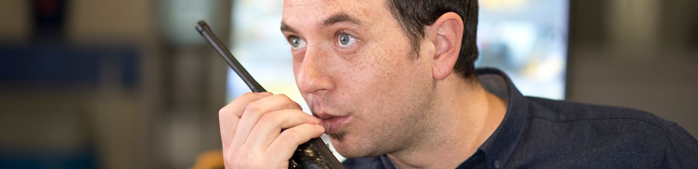 Sicherheitsdienst Ein Mitarbeiter eines Sicherheitsdienstes in dunklem Hemd spricht in sein Funkgerät.