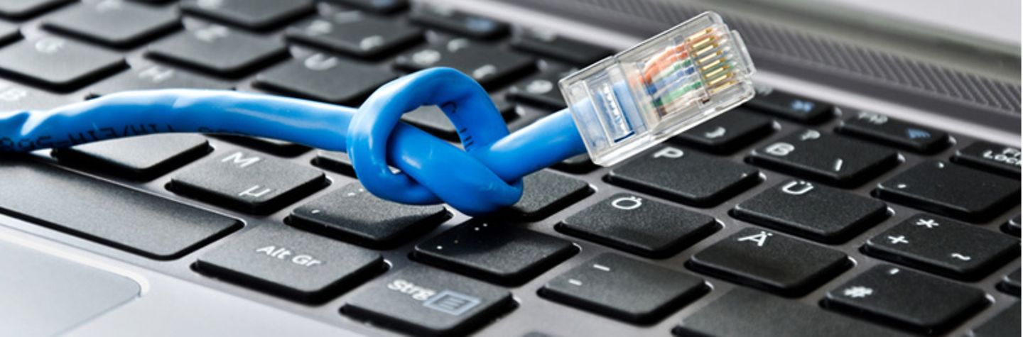 LAN-Kabel mit Knoten liegt auf einer Computertastatur.