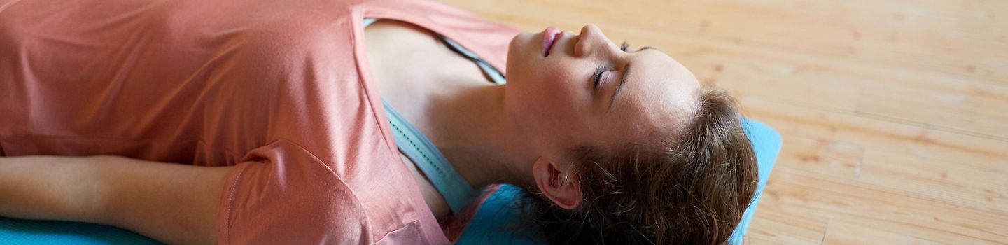 Entspannungskurs Yogagruppe liegt auf Matten
