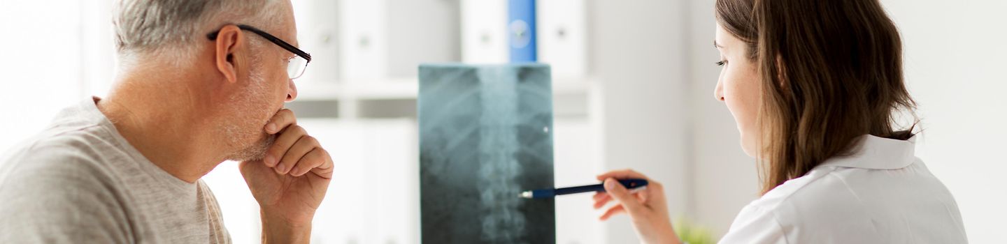 Orthopäde erklärt Patientin Röntgenbild mit Wirbelsäule