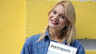 Frau hält BGW magazin im Arm Junge Frau hält das BGW magazin in der Hand und lächelt.