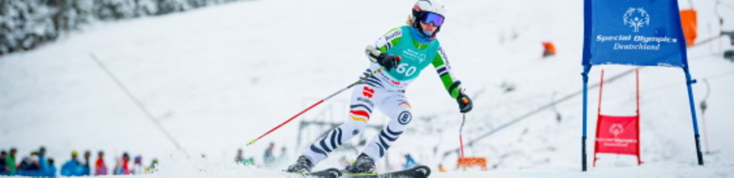Eine Skifahrerin fährt an einem Skihang eine Slalomstrecke entlang