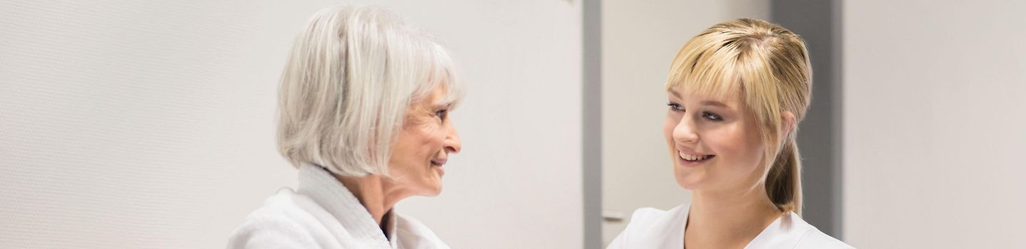 PC770831 Pflegerin spricht mit Seniorin im Rollstuhl