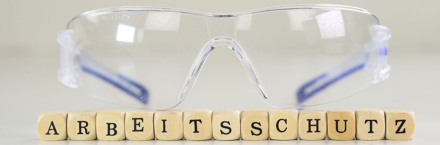 Symbolbild Arbeitsschutz Schutzbrille mit Scrabble-Steinen "Arbeitsschutz"