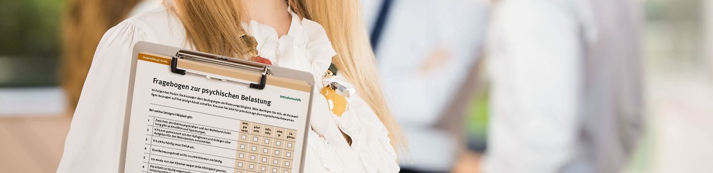 Geschäftsfrau Junge Frau trägt ein Klemmbrett. Im Hintergrund stehen andere Personen.