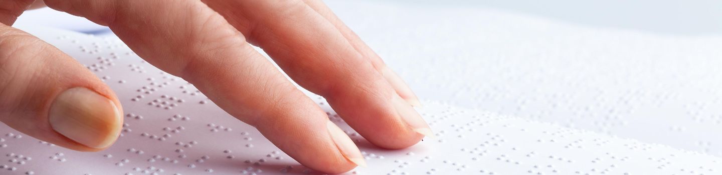 Blindenschrift Finger tasten über eine Buchseite in Blindenschrift.