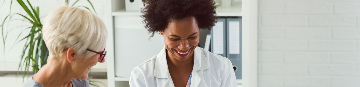 Ärztin bespricht mit einer älteren Patientin Untersuchungsergebnisse.