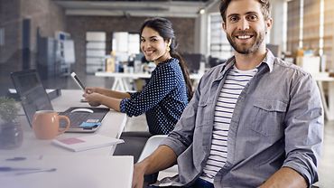 Seminarmotiv 2018 Titel: Bildung und Beratung für Sicherheit und Gesundheit im Betrieb 2018 - zwei junge Leute arbeiten in einem Großraumbüro