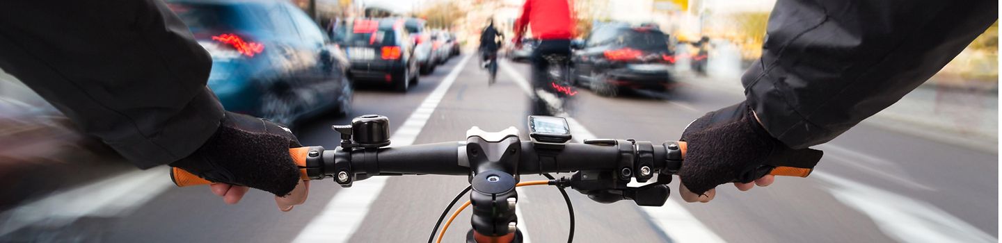Radfahrer fährt auf dem Radweg durch den Stadtverkehr - Bild aus der Perspektive des Radfahrers.