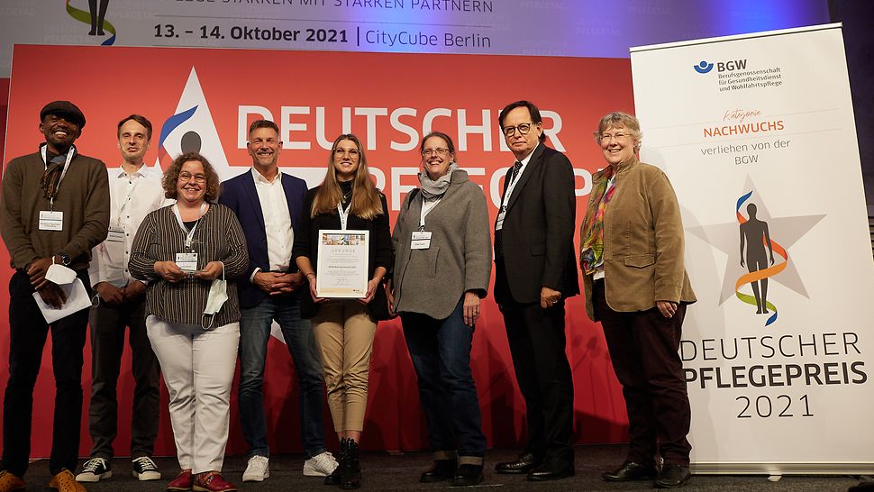 Das Siegerteam des Nachwuchspreises sowie zwei Mitglieder der Selbstverwaltung auf dem Deutschen Pflegetag