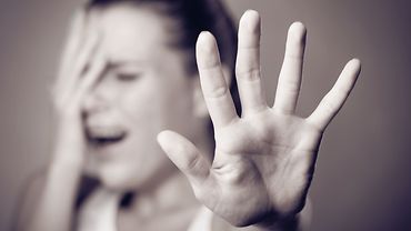 Gewalt und Aggression - Abwehrhaltung Eine Hand wird in Abwehrhaltung gehoben. (Schwarz-weiß-Bild)