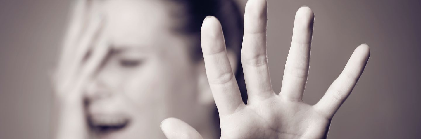 Eine Hand wird in Abwehrhaltung gehoben. (Schwarz-weiß-Bild)