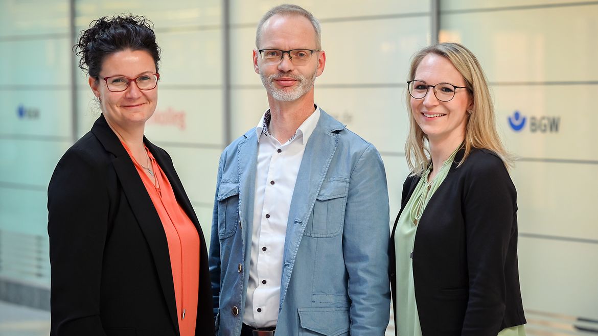 Zwei Frauen und ein Mann stehen vor dem BGW Rückenkolleg