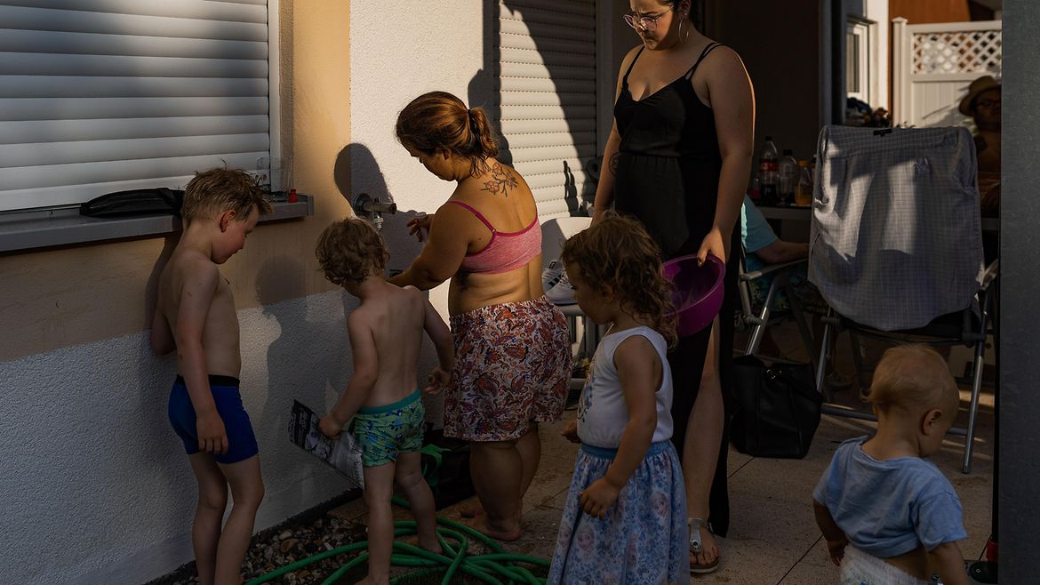 Eine kleinwüchsige junge Frau füllt Wasserbomben auf der Terrasse. Links von ihr stehen zwei Jungen, hinter ihr ihr ein Mädchen und rechts eine weitere Frau.