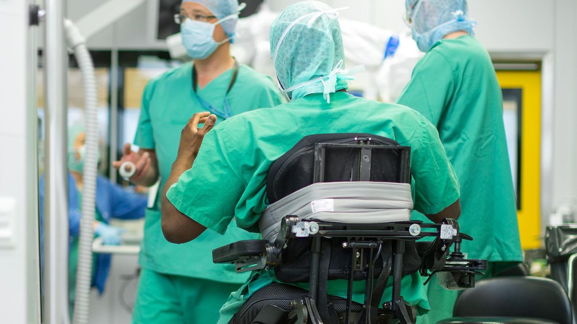 OP-Team im Krankenhaus - ein OP-Mitarbeiter sitzt in einem höhenverstellbaren Rollstuhl.
