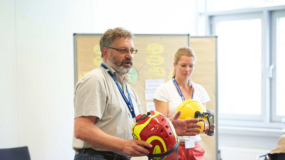 Teilnehmende eines Workshops Teilnehmer eines Workshops hält Schutzhelm in der Hand und zeigt ihn anderen Personen bei einer BGW Sifa-Fachtagung