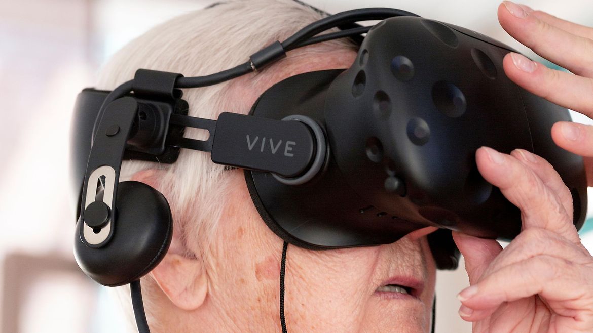 Eine ältere Frau hat eine VR-Brille aufgesetzt.