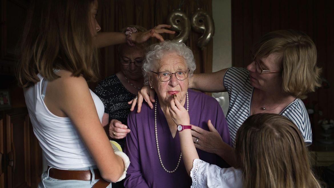 Eine ältere Frau wird von drei jungen Frauen geschminkt.