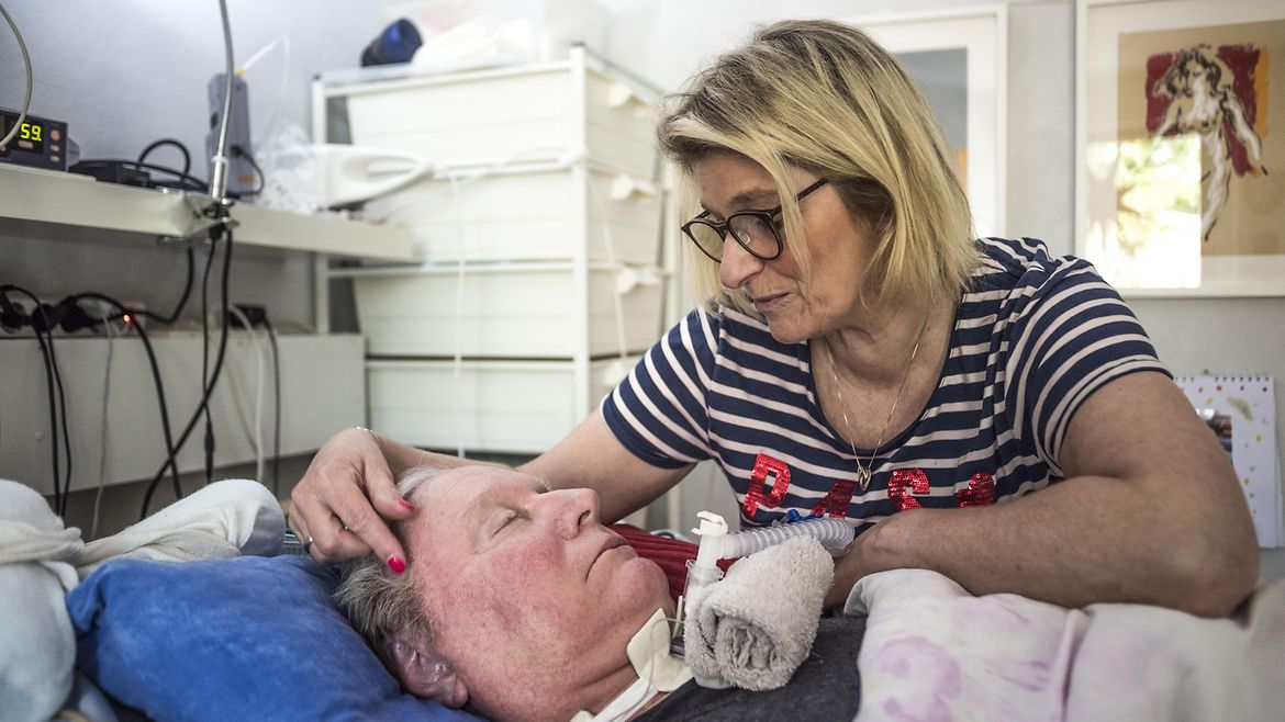 Eine Frau beugt sich über einen Mann im Bett.