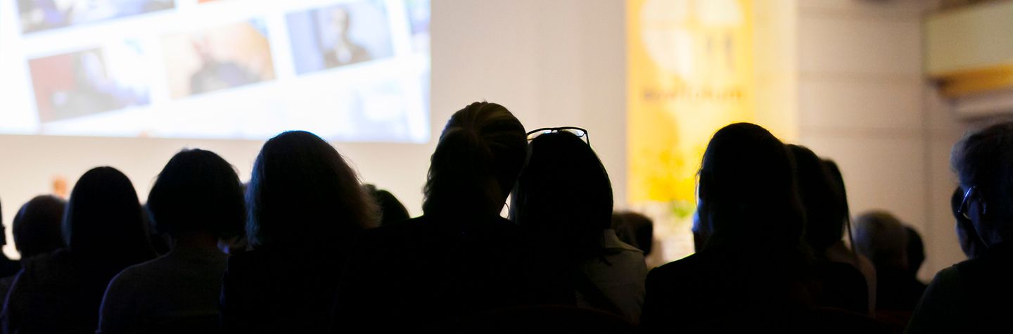 Zuschauer Kongress, Ansicht von hinten Ansicht einer Reihe von Menschen von hinten, die auf eine helle Bühne schauen