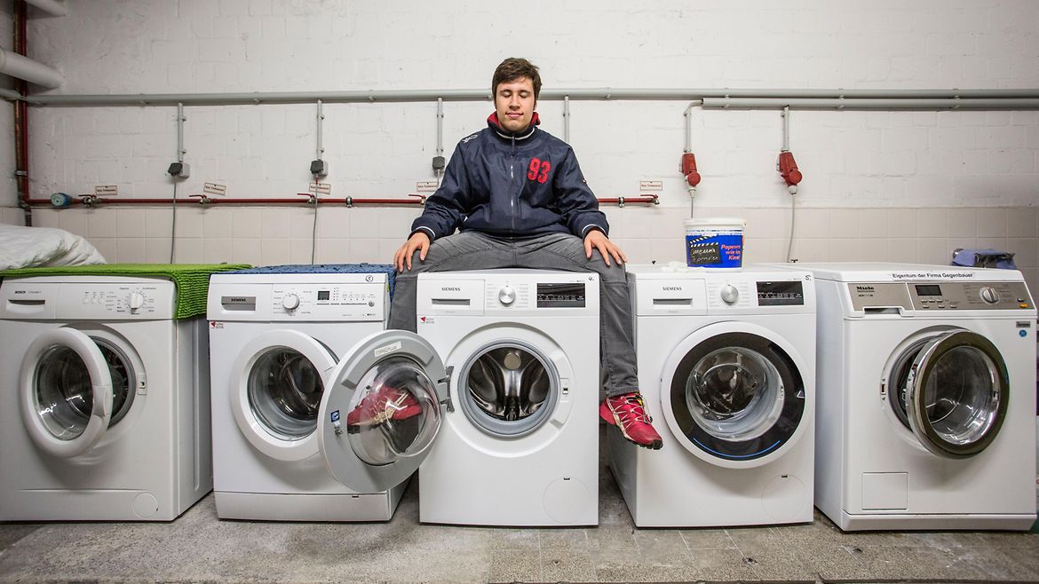 Ein Mann sitzt auf der mittleren von fünf Waschmaschinen.