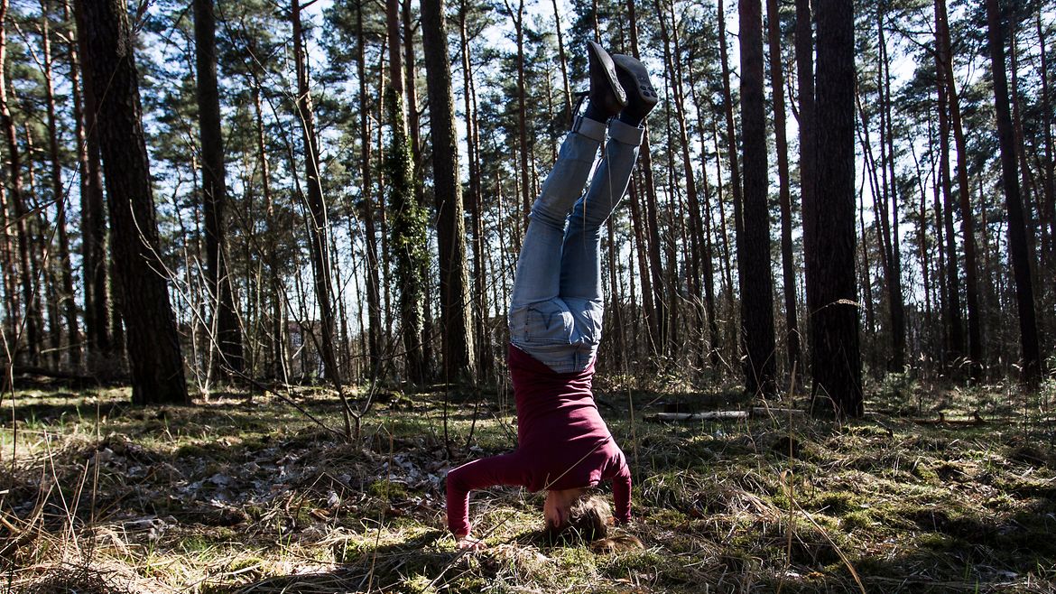 Eine Frau macht einen Kopfstand im Wald.