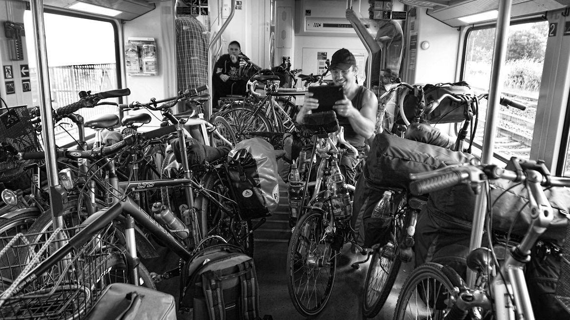 Ein Mann sitzt zwischen vielen Fahrrädern im Zug.