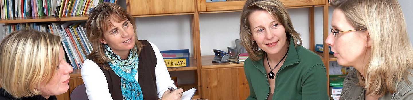 Gesprächsrunde Mehrere Frauen in einem Gespräch am Tisch mit Unterlagen