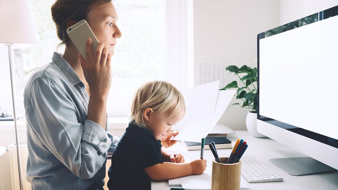 Stressfaktoren im Homeoffice Frau mit Kind auf dem Schoß arbeitet zu Hause - sie telefoniert.