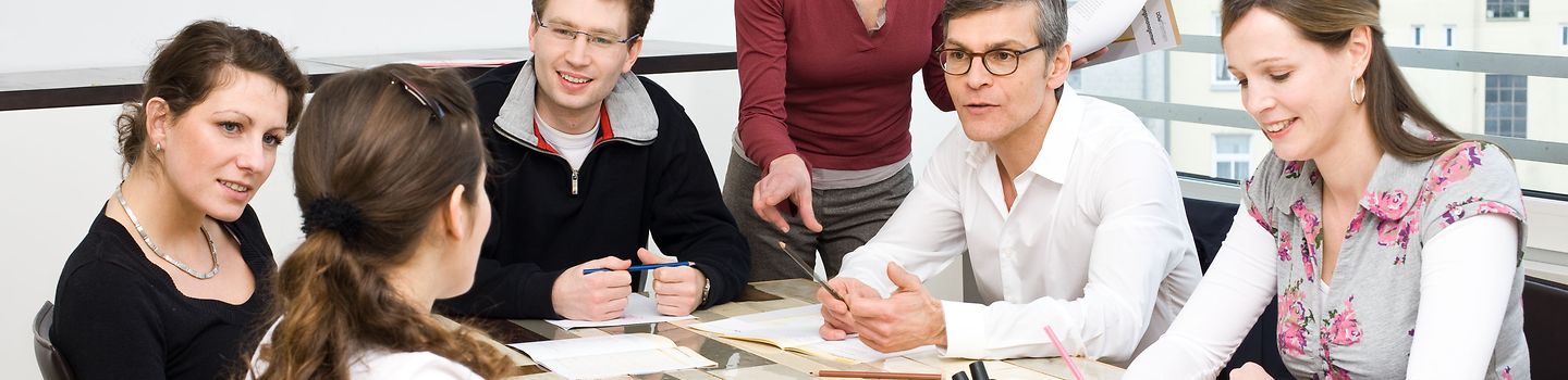 Sechs Personen an einem Tisch bei einer Besprechung.