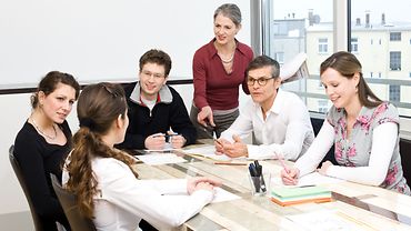 Sechs Personen an einem Tisch bei einer Besprechung.