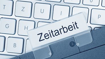 Tastatur, auf der das Schild Zeitarbeit liegt.