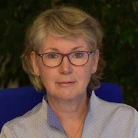 Dr. Grita Schedlbauer Dr. Grita Schedlbauer sitzt an einem Schreibtisch.